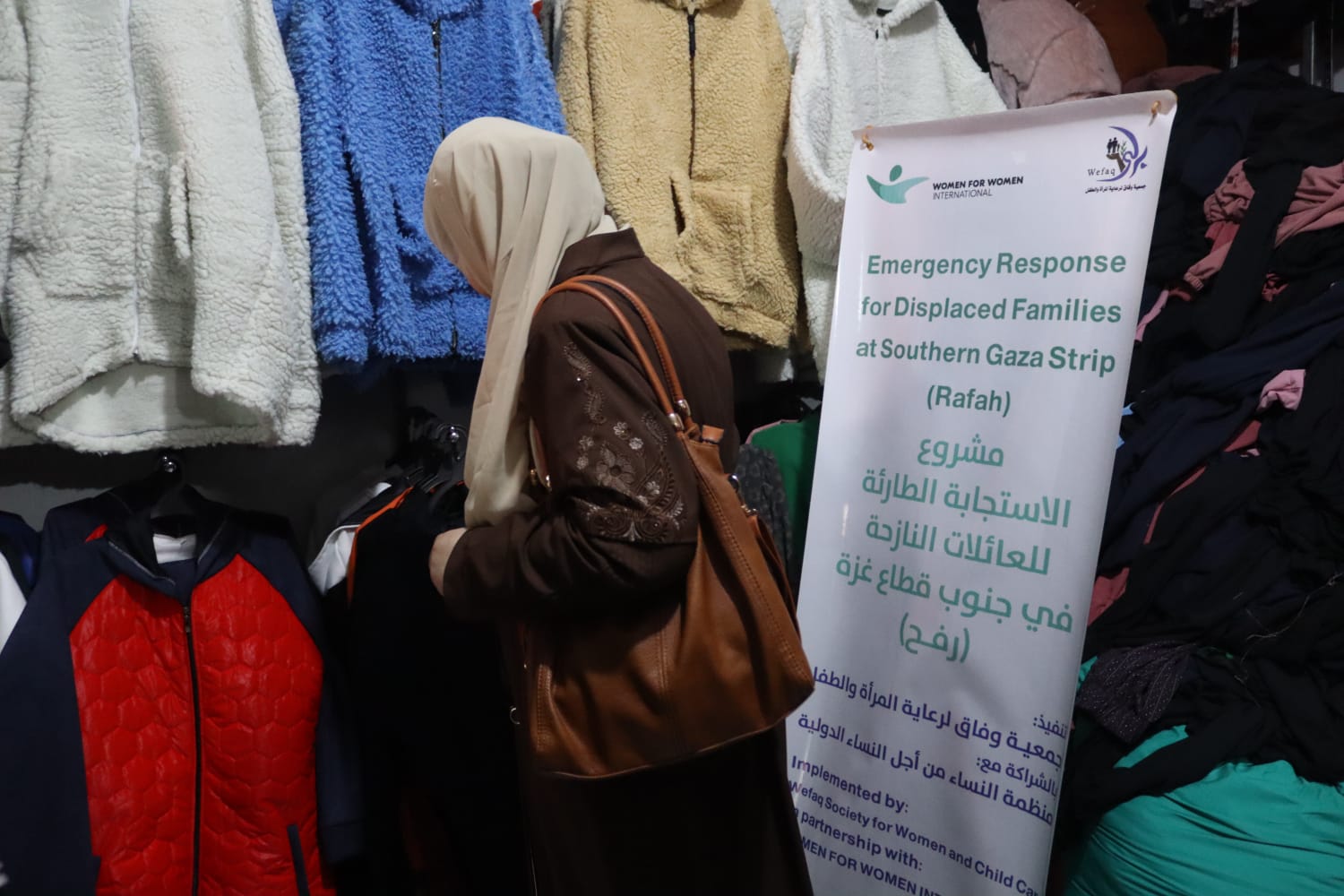 A woman browses for clothing for herself and her family. Although everything is provided for free via vouchers, the shopping experience restores dignity.